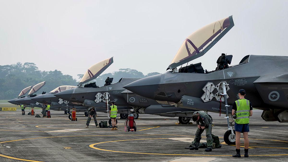 Several Air Force personnel in high-vis attend to four aircraft with their cockpits open.