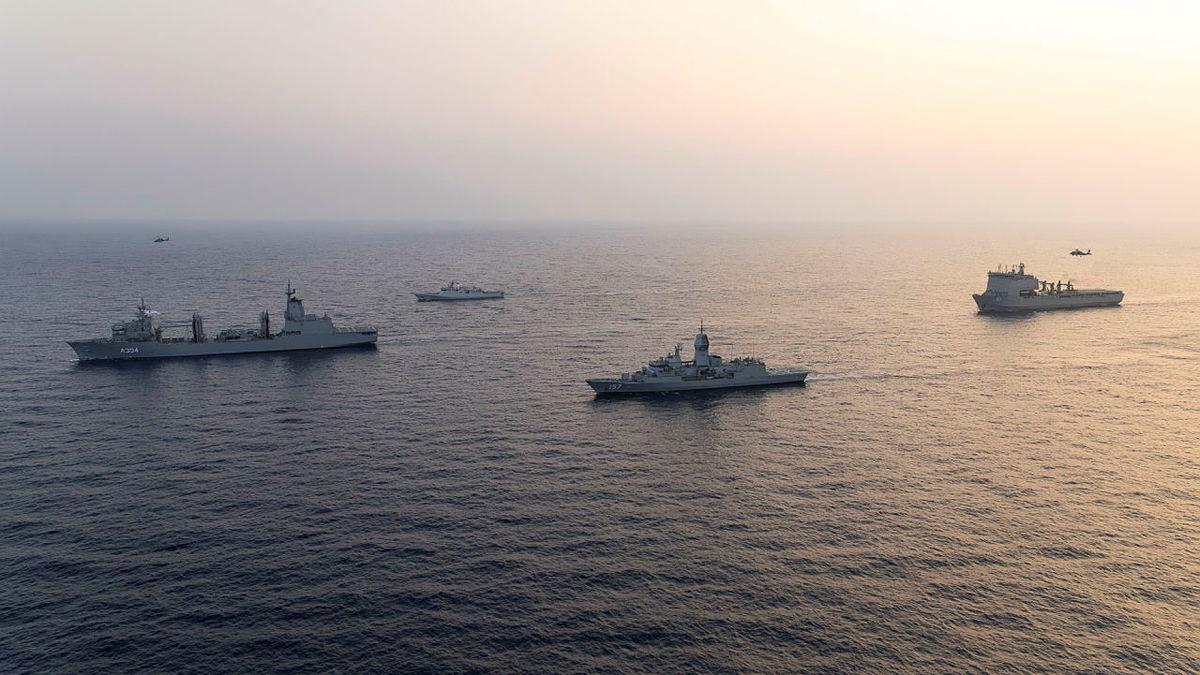 Four ships sail together in the ocean.